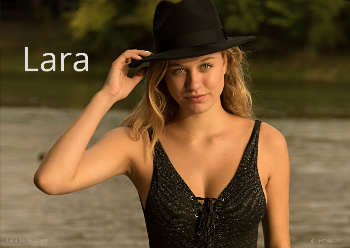 model-Lara2 Blondes Mädchen im schwarzen Badeanzug und Hut steht im Fluß